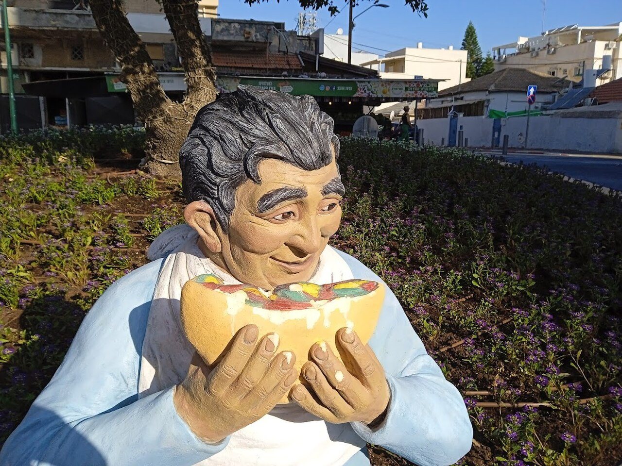 פסל צבעוני של גבר המחזיק בפיתה עם סביח בכיכר הסביח ברמת גן