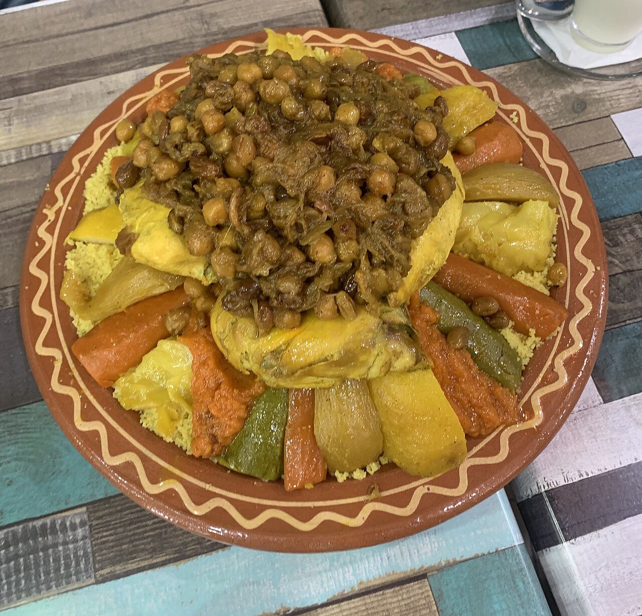 ערימת קוסקוס עם ירקות וחומוס בצלחת חרס
