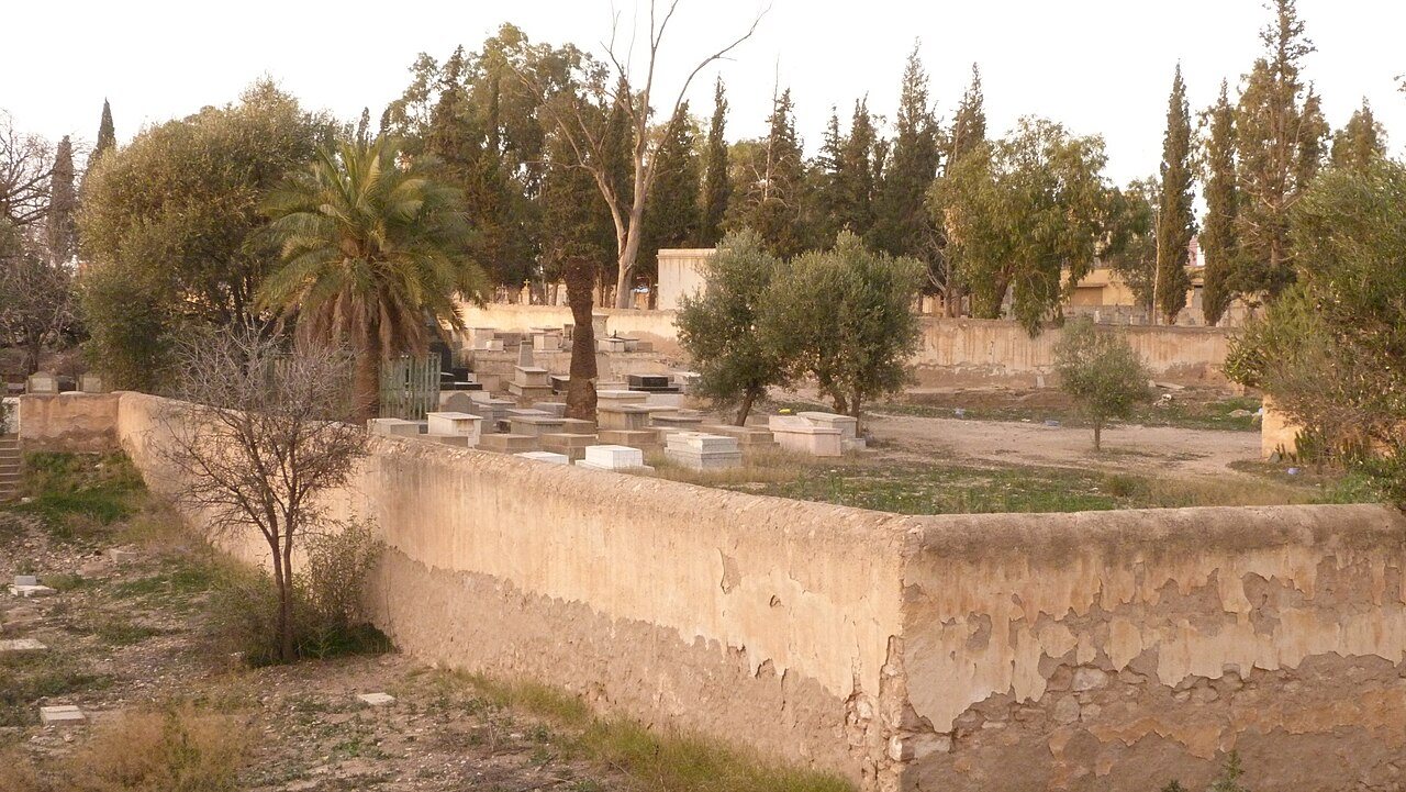 מצבות שטוחות מאחורי חומה נמוכה בין עצים