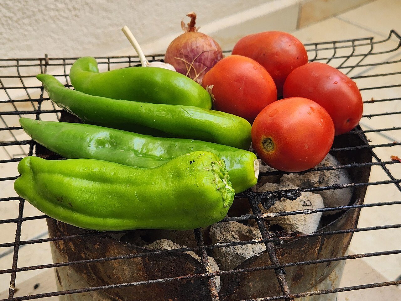 ירקות טריים כולל פלפלים ירוקים ועגבניות נצלים על רשת מנגל