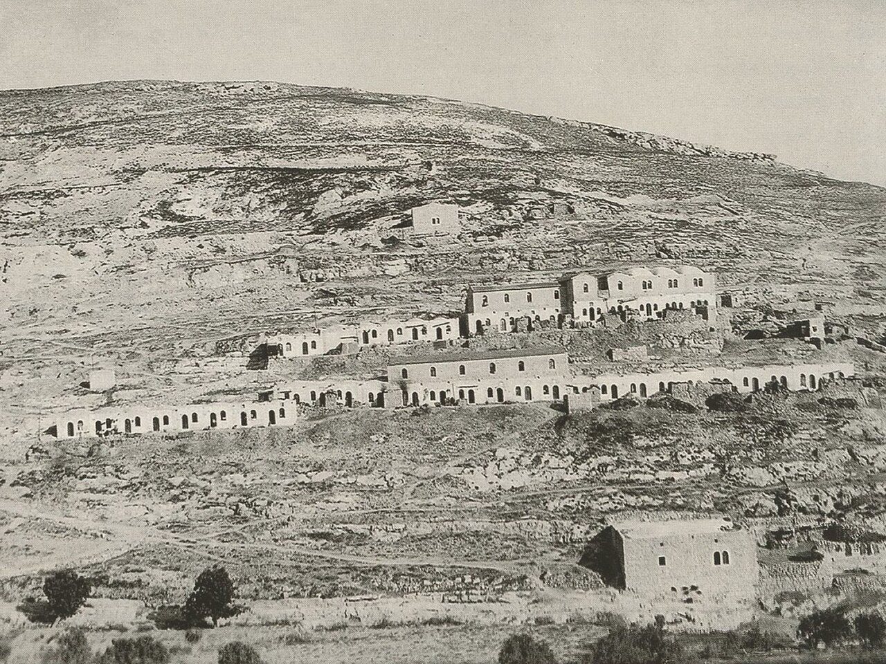 שורות של בתי אבן נמוכים על מדרון סלעי וחשוף